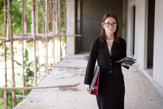 Businesswoman standing holding a file and a calculator.