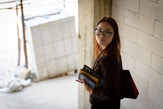 A businesswoman holds a calculator while walking down a stairwell in a building under construction.