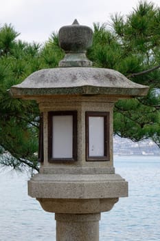 Stone lantern in Japanese garden with green tree background.