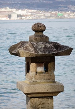 Stone lantern in Japanese garden with seascape background.