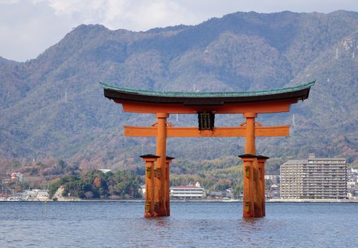 Floating gate (Giant Torii) of Itsukushima Shrine with cityscape background in Hiroshima, Japan. The historic shrine complex is listed as a UNESCO World Heritage Site.