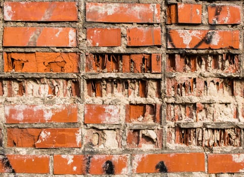 A fragment of a wall from an old red partially destroyed clay brick
