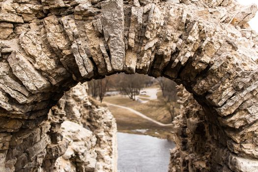 A fragment of a stone arch from limestone. Ruins of a medieval Russian fortress. Remains of the entrance to the tower.