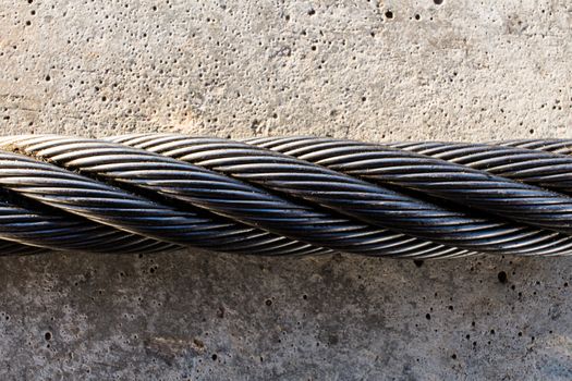 Twisted steel rope on a gray concrete slab.