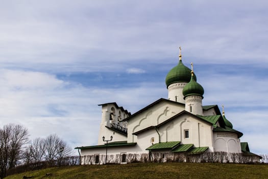 The building of the ancient Russian church in Pskov against the background of a cloudy sky in the spring day