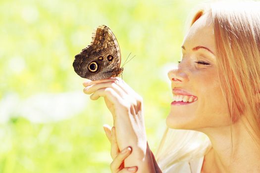 Woman playing with a butterfly on green grass