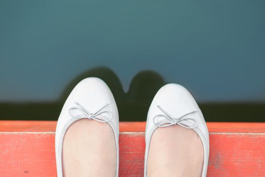 Female feet on the edge of the pier