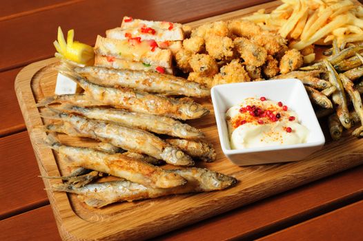 big wooden board with fried fush, mussels, french fries served as companion for beer or other alcool drinks