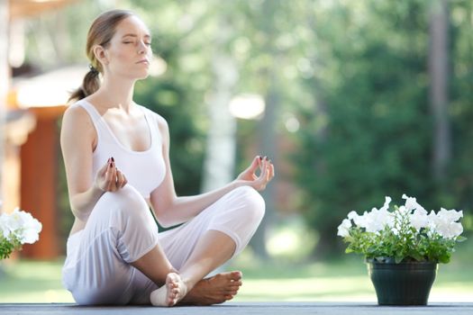 Young woman doing yoga lotus exercise outdoors