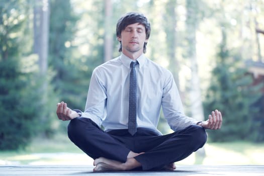 Businessman in suit practicing yoga in park