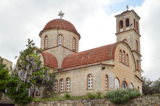 Orthodox church with purple lilac at the entrance to the island of Crete