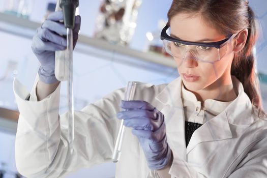 Life scientists researching in laboratory. Focused female life science professional pipetting solution into the glass cuvette. Lens focus on researcher's eyes. Healthcare and biotechnology concept.
