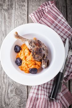 Roasted duck leg with mashed carrot and dried prunes.