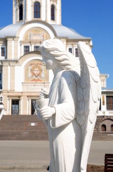 Angel statue against ancient Russian Cathedral in Diveevo city