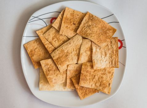 homemade spicy pita chips made from pita bread with olive oil and spices in white plate on white background