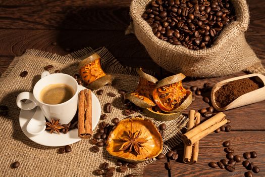 Coffee cup with cinnamon, star anise, dried orange fruit and coffee sack seen from above