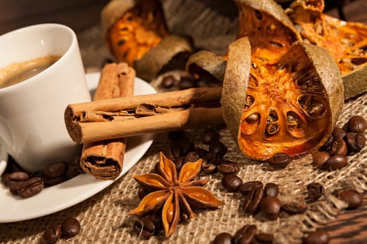 Close-up of cup of coffee with cinnamon, dried orange fruit and star anise