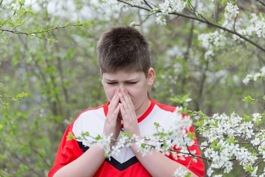 teenage Boy with allergic rhinitis in  spring garden