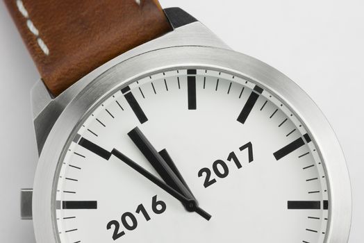 Traditional watch with analog conceptual visualization of the turn of the year from two thousand sixteen to two thousand seventeen
