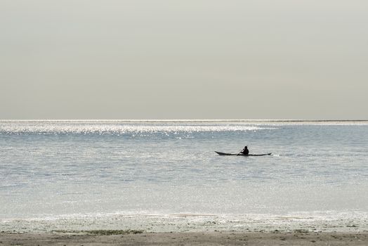 Canoeist on the Wadden Sea at Vlieland in the reflection of the sunlight of the water
