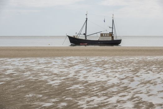 Fishing boat on the beach of the Wadden Sea near the island of Terschelling in the North of the Netherlands
