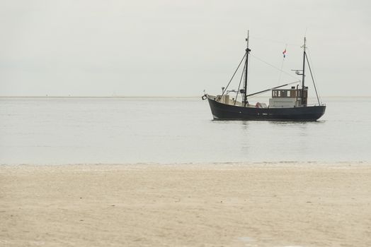 Fishing boat on the beach of the Wadden Sea near the island of Terschelling in the North of the Netherlands
