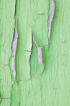 Cracking and peeling green paint on a wall. Vintage wood background with peeling paint. Old board with Irradiated paint