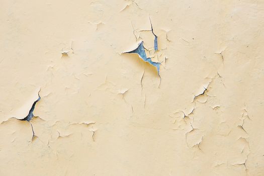 Cracking and peeling yellow paint on a wall. Vintage wood background with peeling paint. Old board with Irradiated paint