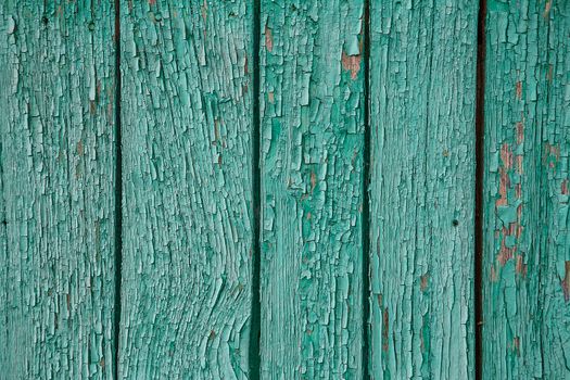 Cracking and peeling blue paint on a wall. Vintage wood background with green peeling paint. Old board with Irradiated paint