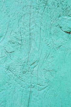 Cracking and peeling turquoise paint on a wall. Vintage wood background with peeling blue paint. Old board with Irradiated paint