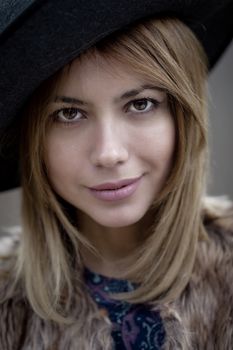 outdoor portrait of a pretty young woman wearing a hat, looking at camera