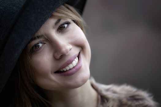 outdoor portrait of a pretty young woman wearing a hat, looking at camera