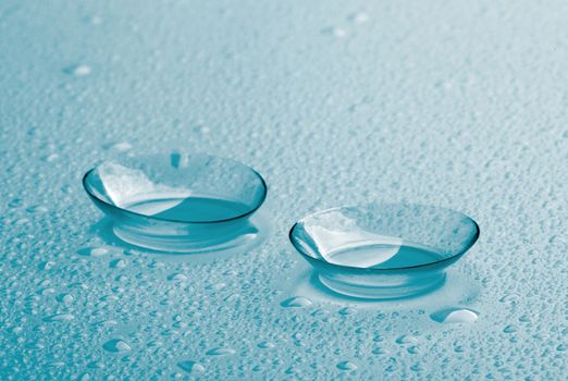 Turquoise Contact Lenses with Water Droplets isolated on Toned Wet background