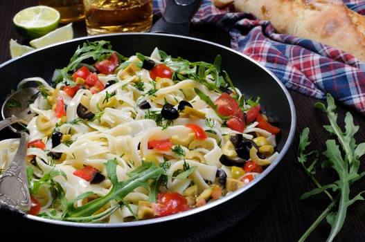 Pasta with crushed olives and cherry tomatoes, arugula. Horizontal shot.