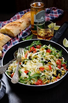 Pasta with crushed olives and cherry tomatoes, arugula. Vertical shot.
