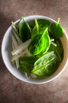 A Spinach Salad with apple on a stone surface