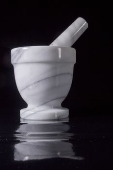 White marble mortar with a pestle on a black background