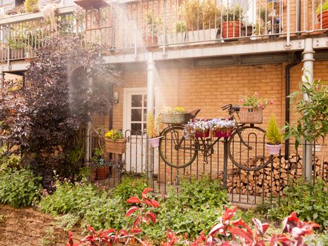 beautiful outside garden scene with a bike with flowers in basket and plant pots summer late afternoon light