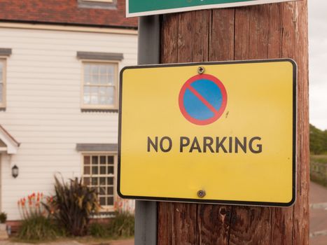 a yellow warning traffic sign outside saying no parking allowed on wood pole