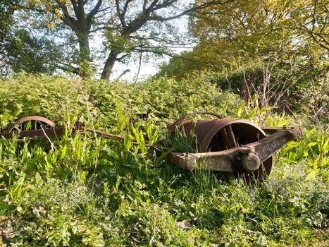 an old retro rusted farm machine plow on the ground unused outside nice light