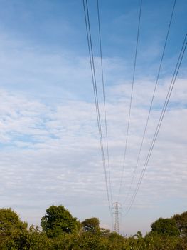 electric wires on a pylon in the distance spreading across the clear blue and cloudy sky beautiful communication peace