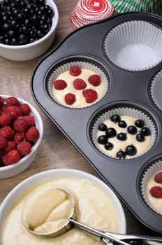 Preparation for baking muffins stuffed with raspberries and black currants