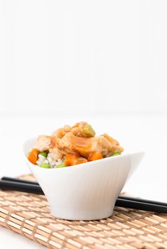 Small bowl of general tao spicy chicken on vegetable rice.