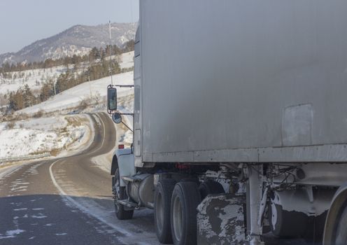 Speeding truck wheels on icy road during winter storm.