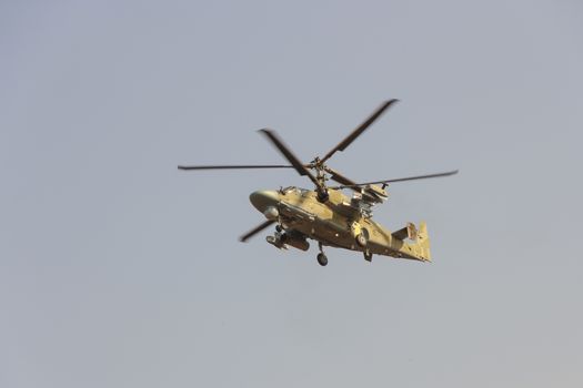 Green helicopter flies against the blue sky.