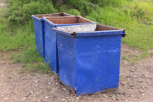 Three empty garbage cans on the green grass.