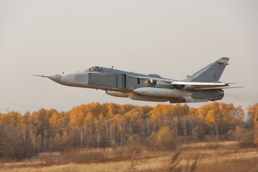 Military jet bomber Su-24 Fencer flying above ground.