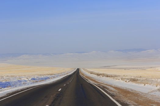 Winter road leaving into distance into the mountains.