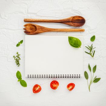 Foods background and Food menu design . Various herbs ingredients sweet basil, sage ,lemon thyme ,rosemary, cherry tomatoes sliced setup with white notebook on white shabby table.