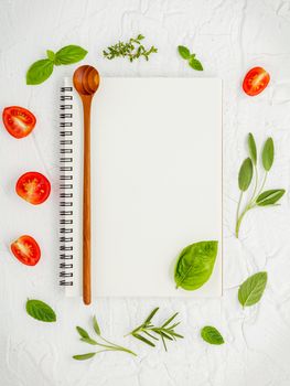 Foods background and Food menu design . Various herbs ingredients sweet basil, sage ,lemon thyme ,rosemary, cherry tomatoes sliced setup with white notebook on  white shabby table.
